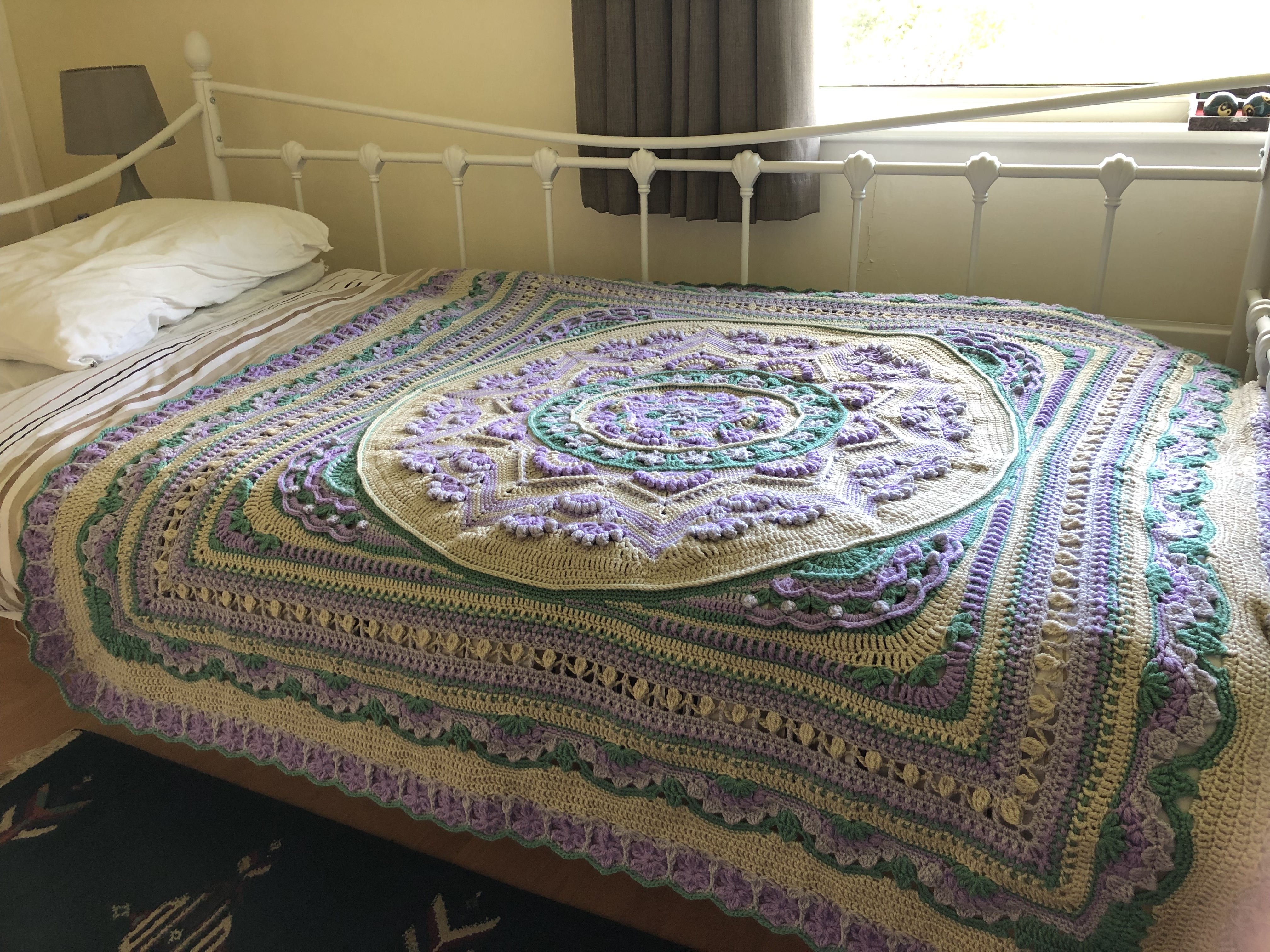 A crochet blanket laid over a single bed